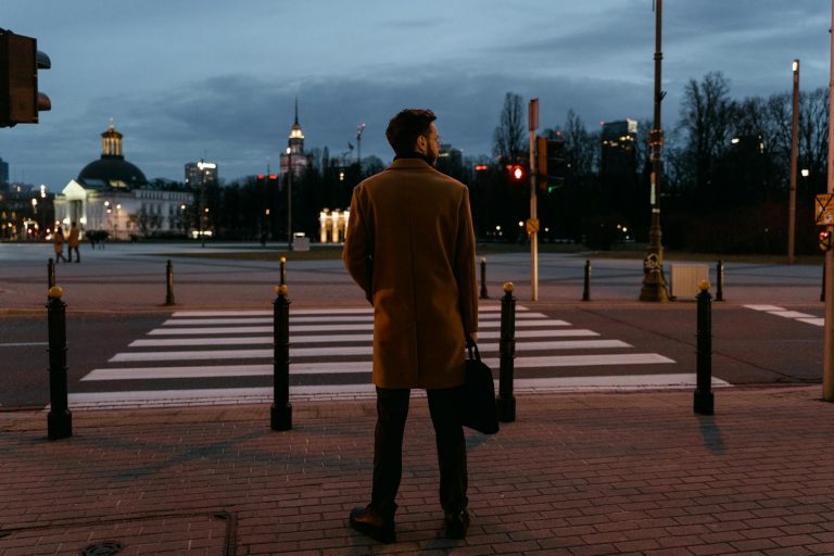 professional person in casual clothes standing at crossroads, one path leads to busy marketplace with people working (creators), other path leads to people sitting watching screens (consumers), urban setting, natural lighting, realistic photography style, search term: crossroads decision business — Formations 90